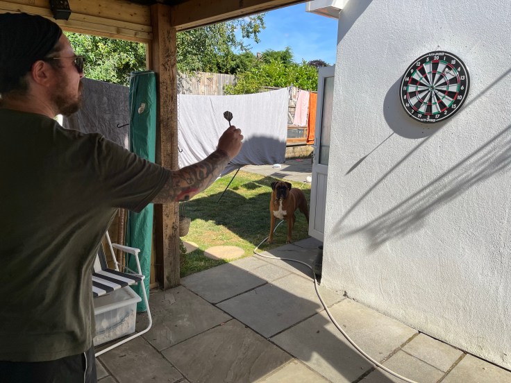 A man playing darts in a garden bar